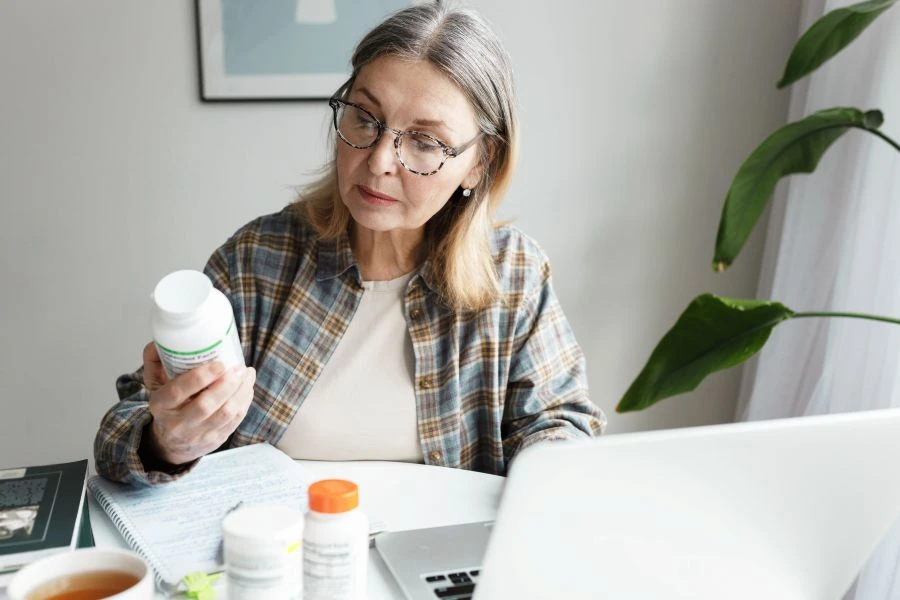 Woman checking a supplement bottle on computer